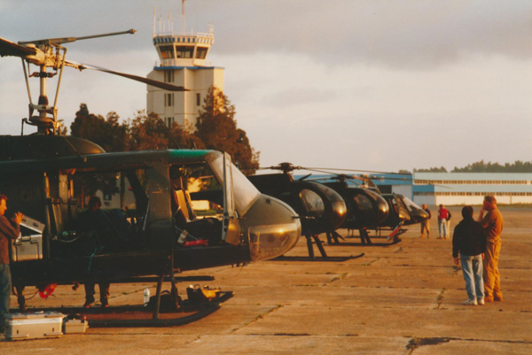 Jerry Grayson's Huey in the foreground, then the two Little Birds, then the Twin Squirrel camera ship. Bobby “Zee” is at the right, talking to Cameraman Mike Kelem. In the distance is Marc Wolff (Aerial Director) talking to Dennis. - Photo: Jerry Grayson
