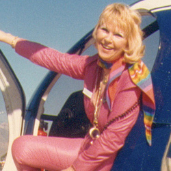 Rosemary Arnold sporting a pink flight suit in a Hughes 500